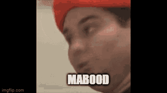 a man wearing a red hat is making a funny face with the word mabood written on his face .