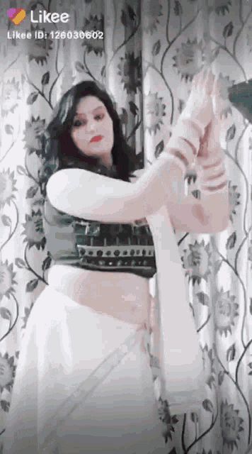 a woman in a white saree is dancing in front of a curtain with likee written on the bottom