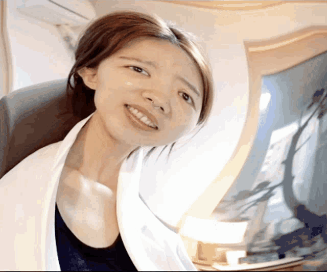 a woman in a white coat is smiling and looking at the camera