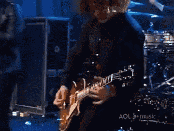a man playing a guitar in front of a drum set with the words aol music on the bottom
