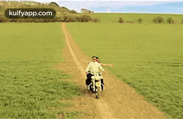 a couple riding a motorcycle down a dirt road .