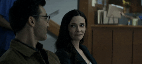 a man and a woman are sitting in a waiting room with a nurse in the background