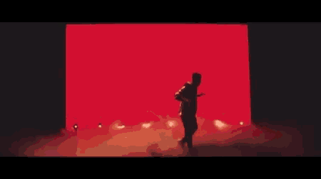 a man is dancing in front of a red wall .