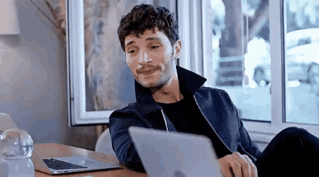 a man is sitting at a table with a laptop computer on it .
