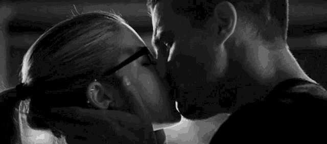 a man and woman are kissing in a black and white photo .
