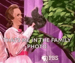 a woman in a pink dress is holding a squirrel .