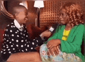 a woman in a green jacket is holding a microphone and talking to a young boy .