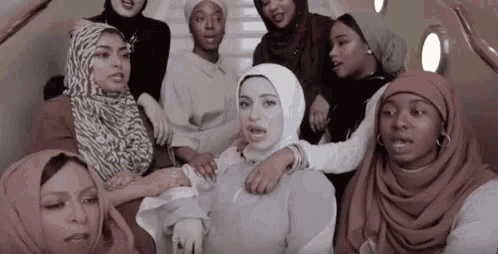a group of women wearing hijabs are posing for a picture .