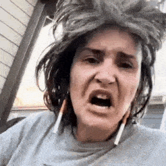 a woman with gray hair is making a funny face while wearing a wig and earrings .