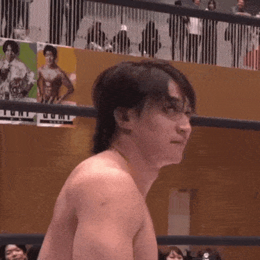 a man without a shirt is standing in a wrestling ring with a poster on the wall that says jump