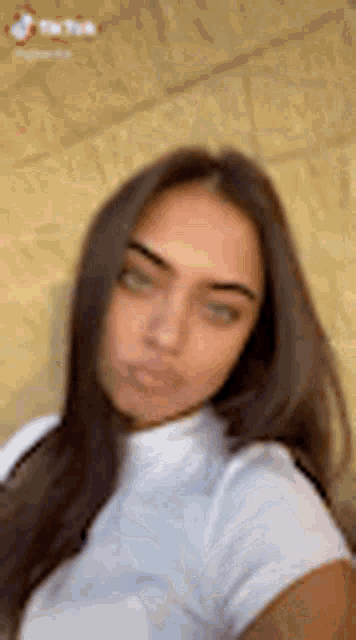a woman with long brown hair and green eyes is taking a selfie with her phone .