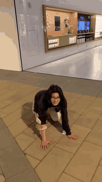 a woman is crawling on the ground in front of a store that says xnote