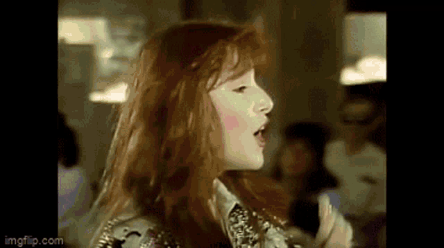 a woman with red hair is singing into a microphone in a room .