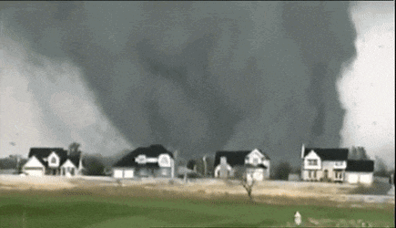 a tornado is moving through a residential area with houses in the background .