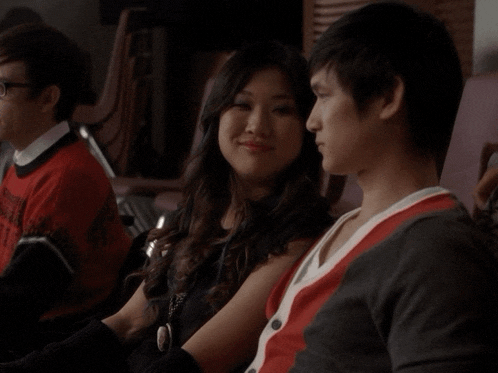 a woman sitting next to a man wearing a red shirt that says ' sydney ' on it
