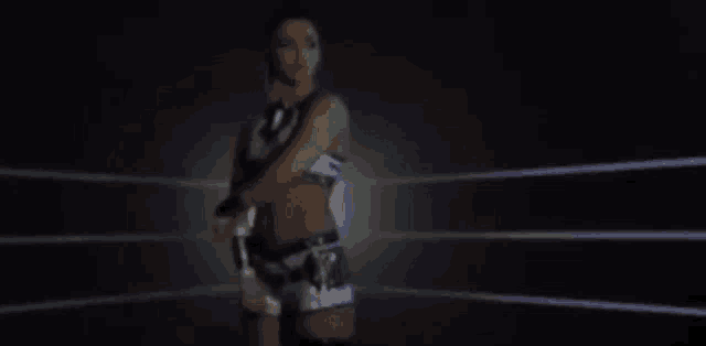 a female wrestler is standing in a ring with her arms crossed .