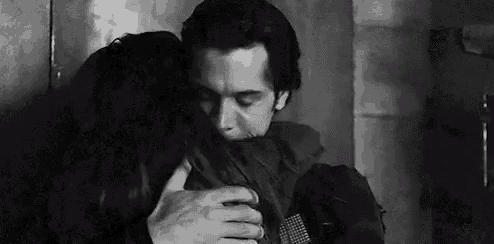 a black and white photo of a man hugging a woman .