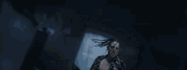 a man with dreadlocks is dancing in a dark room .