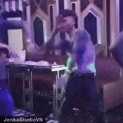 a group of people are dancing in a room with a purple light .