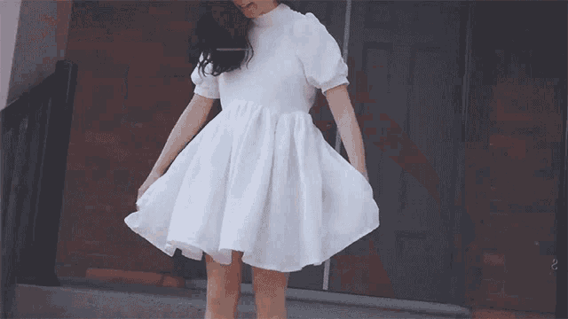 a woman in a white dress stands in front of a wooden door