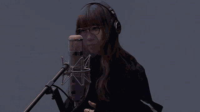 a woman wearing glasses and headphones singing into a yamaha microphone