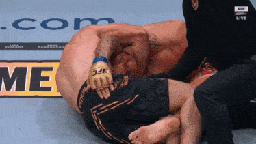 a man in a ufc glove is laying on the ground