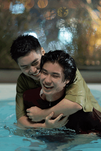 two men are hugging each other in a pool and they are smiling