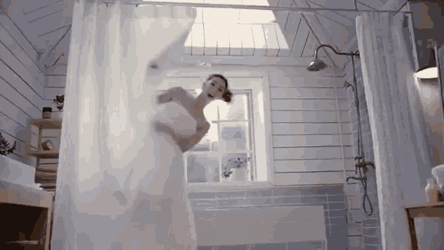 a woman in a towel is standing in a shower
