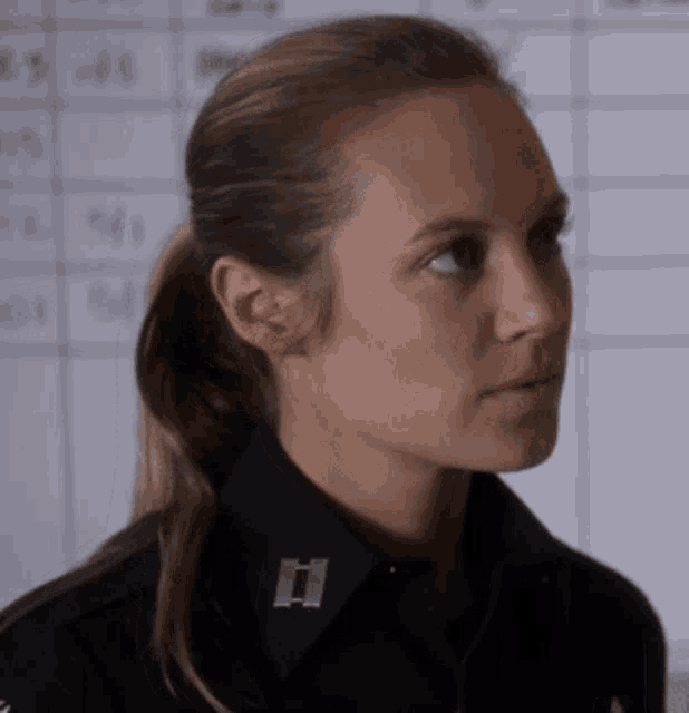 a woman in a police uniform has a badge on her collar with the letter i on it