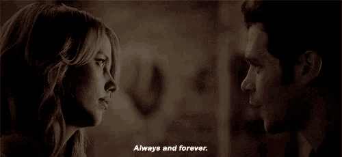 a man and a woman are looking at each other in a dark room and the woman is saying `` always and forever '' .