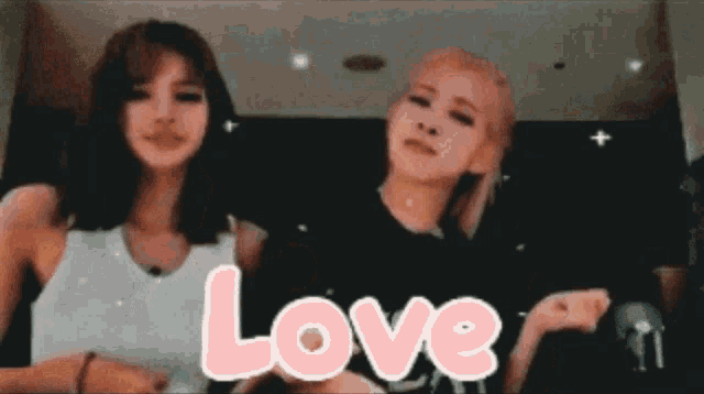 two girls are standing next to each other and the word love is written in pink letters .