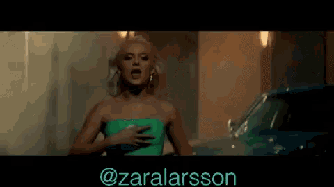 a woman in a green strapless top is standing next to a car with the hashtag @zaralarsson