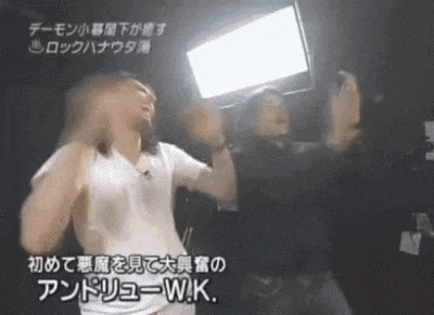 a couple of men are standing next to each other in a dark room with their hands in the air .