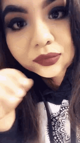 a close up of a woman 's face with red lipstick and a black hoodie .