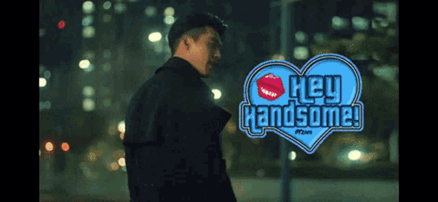 a man is standing in front of a heart that says hey handsome