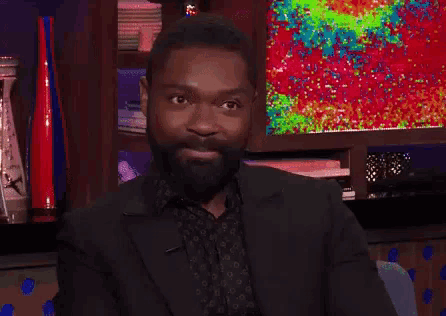 a man with a beard is smiling in front of a television