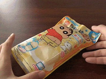 a person is opening a package of crayon shin chan chips