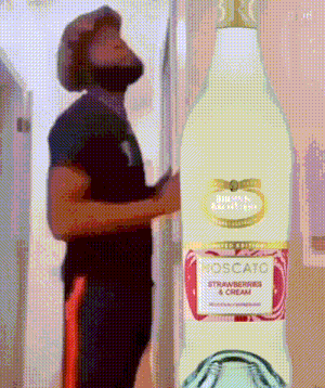 a man standing next to a bottle of moscato