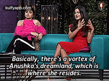 two women are sitting on a blue couch and talking .