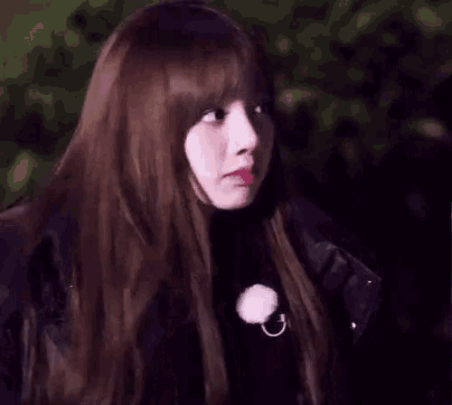 a woman with long brown hair and bangs is wearing a black jacket and a black sweater .