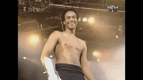 a man without a shirt is dancing on a stage in front of a crowd .