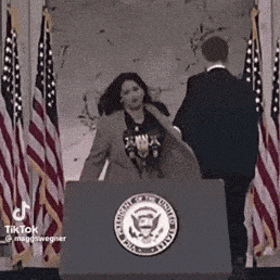 a woman is standing at a podium in front of a man .