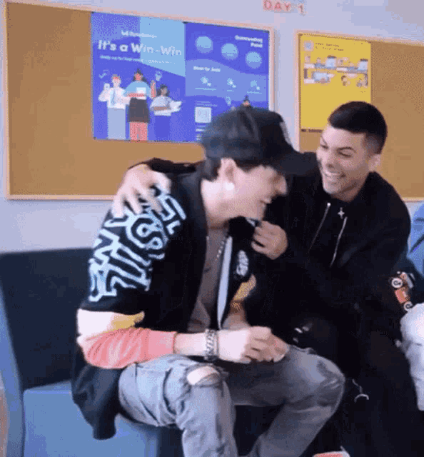 two men are laughing in front of a poster that says it 's a win win