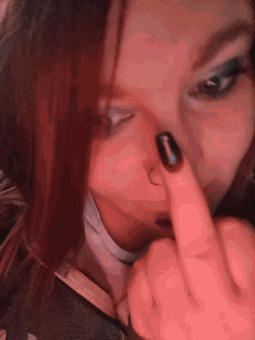 a close up of a woman 's face with a finger pointing to her nose