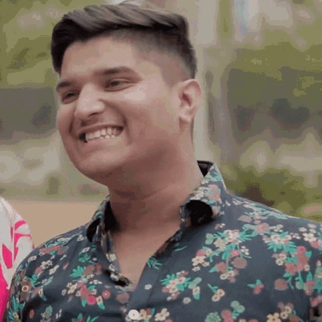 a young man wearing a floral shirt is smiling