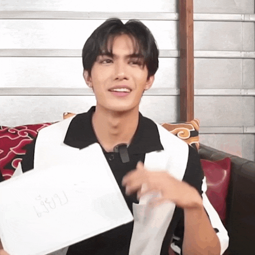 a young man is holding a piece of paper that says " nu "