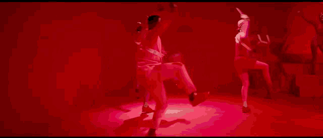 a man in a pink jacket is dancing in front of a red wall .