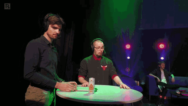 a can of orange juice sits on a table next to a man wearing headphones