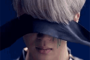 a close up of a man covering his eyes with a black ribbon .