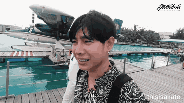 a man is standing on a dock with a plane in the background and the website thisisakate is visible